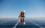 A handyman on the rooftop installing solar panels.